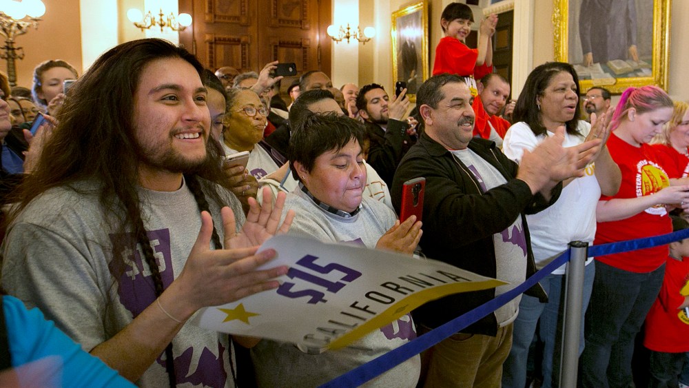 Supporters of a bill to raise California's minimum wage, celebrate outside the state Senate Chamber after the measure was approved by the Senate, March 31, 2016, in Sacramento, Calif. (Photo by Rich Pedroncelli/AP)