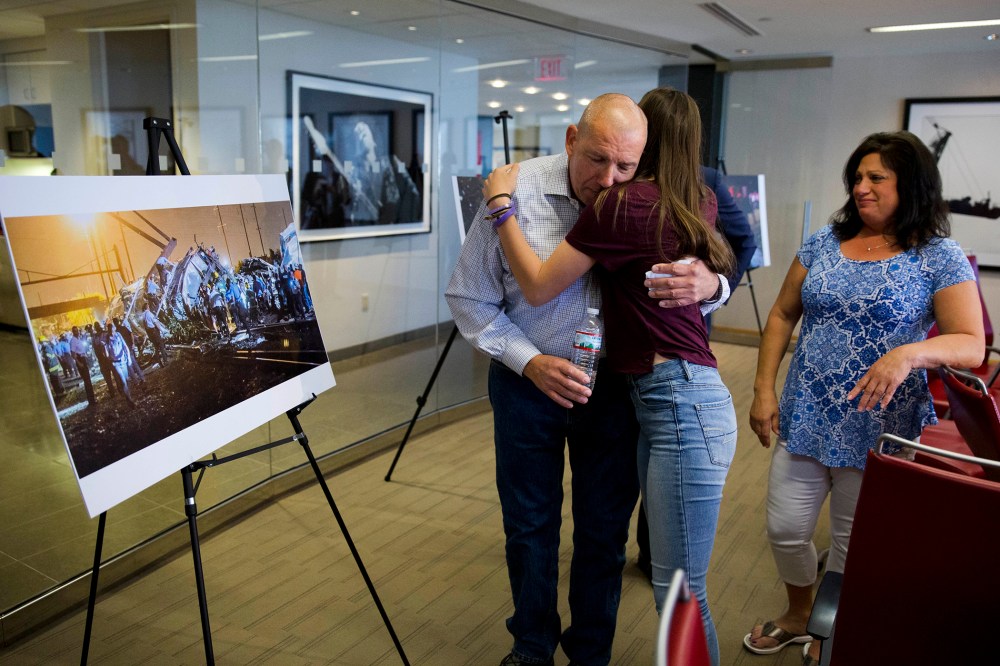 Amtrak crash survivor Robert Hewett embraces his daughter Emily as his wife Judy, right, looks on after a news conference, May 12, 2016, in Philadelphia. (Photo by Matt Rourke/AP)