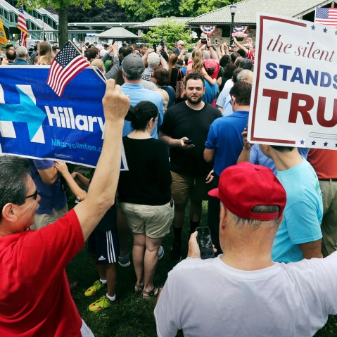 A supporter of Democratic presidential candidate Hillary Clinton and a Republican presidential candidate Donald Trump supporter hold signs as they attend a Memorial Day parade on May 30, 2016, in Chappaqua, N.Y. (Photo by Mel Evans/AP)