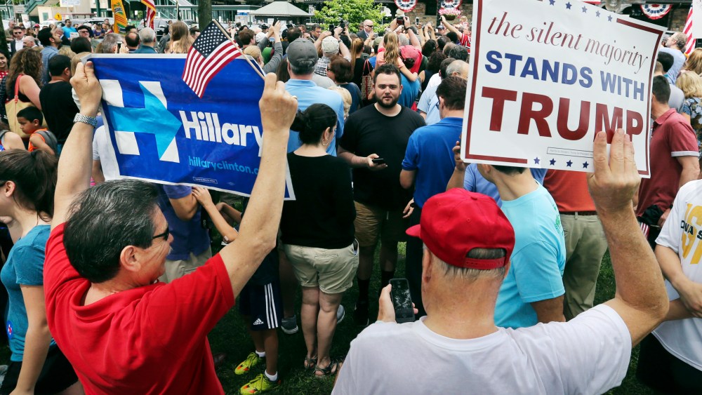 A supporter of Democratic presidential candidate Hillary Clinton and a Republican presidential candidate Donald Trump supporter hold signs as they attend a Memorial Day parade on May 30, 2016, in Chappaqua, N.Y. (Photo by Mel Evans/AP)