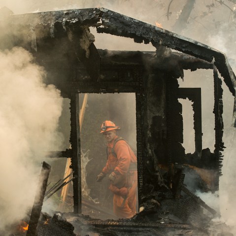 An inmate firefighter examines a burning structure while battling the Loma fire near Morgan Hill, Calif., on Wednesday, Sept. 28, 2016.