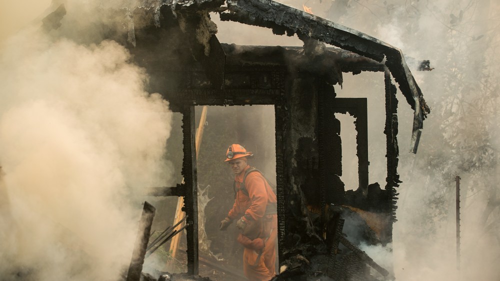 An inmate firefighter examines a burning structure while battling the Loma fire near Morgan Hill, Calif., on Wednesday, Sept. 28, 2016.