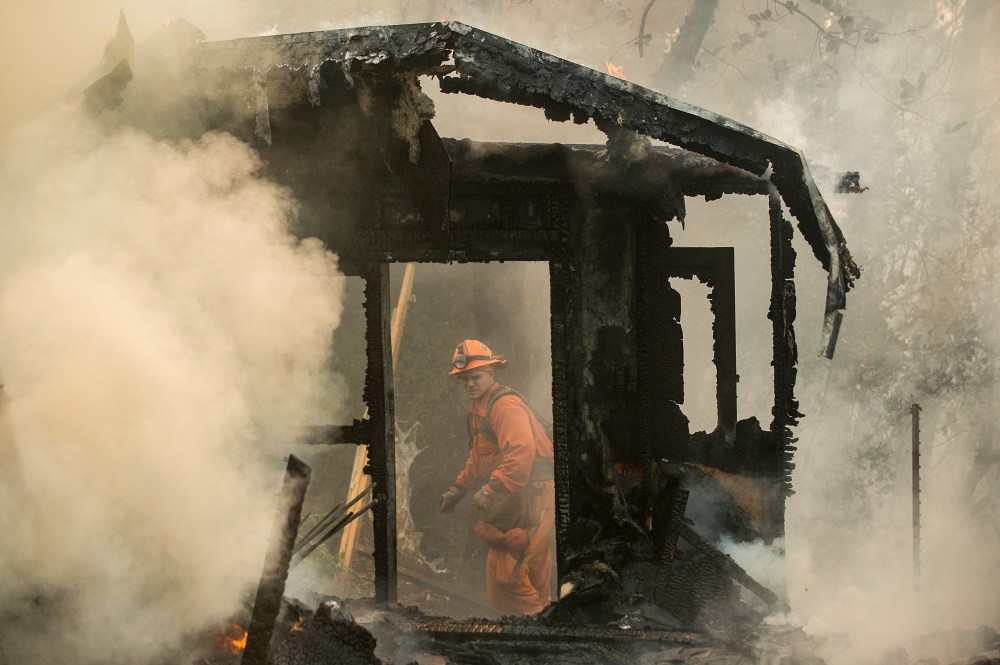 An inmate firefighter examines a burning structure while battling the Loma fire near Morgan Hill, Calif., on Wednesday, Sept. 28, 2016.