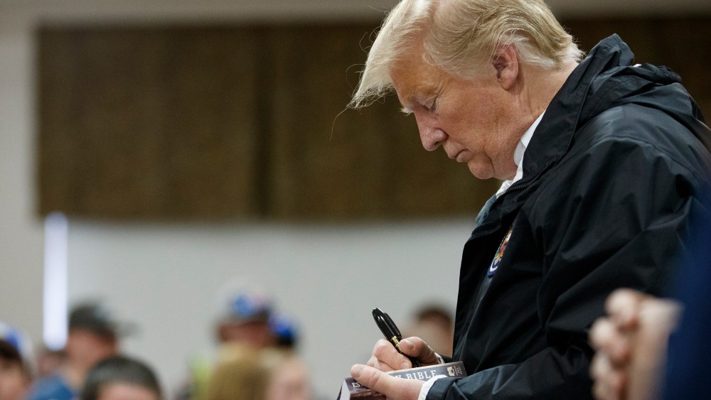 President Donald Trump signs a Bible as he greets people at Providence Baptist Church in Smiths Station, Ala., Friday, March 8, 2019, during a tour of areas where tornadoes killed 23 people in Lee County, Ala.