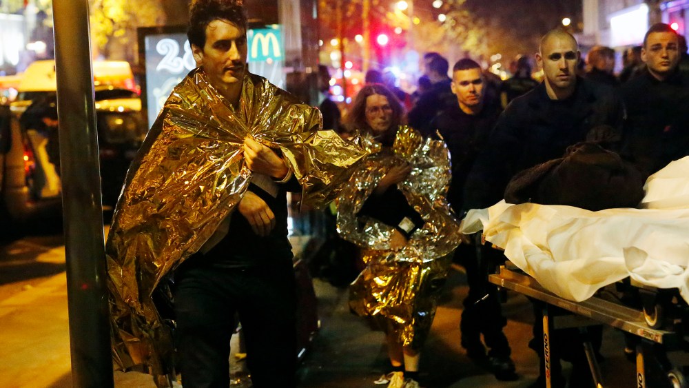 Victims walk away outside the Bataclan theater in Paris, Nov. 13, 2015. (Photo by Jerome Delay/AP)
