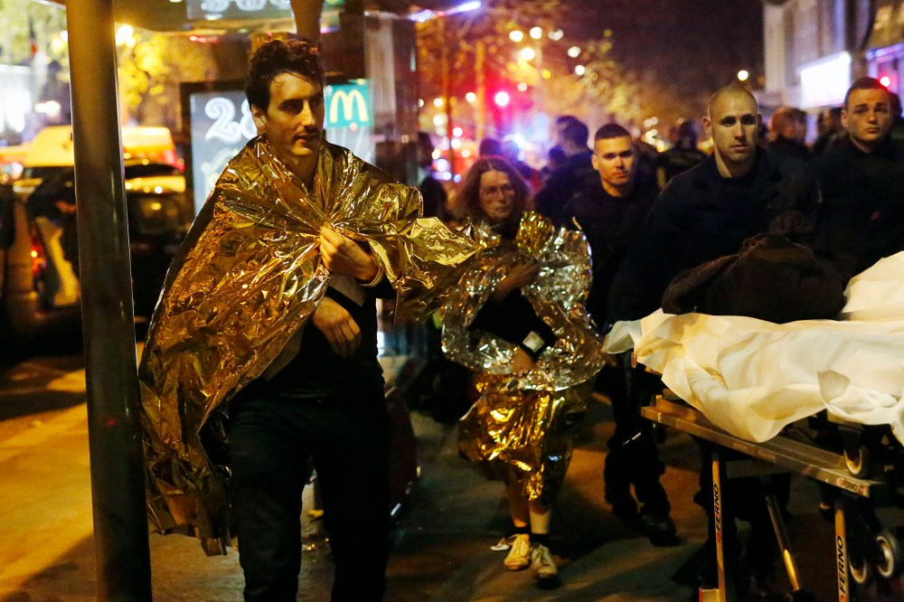 Victims walk away outside the Bataclan theater in Paris, Nov. 13, 2015. (Photo by Jerome Delay/AP)