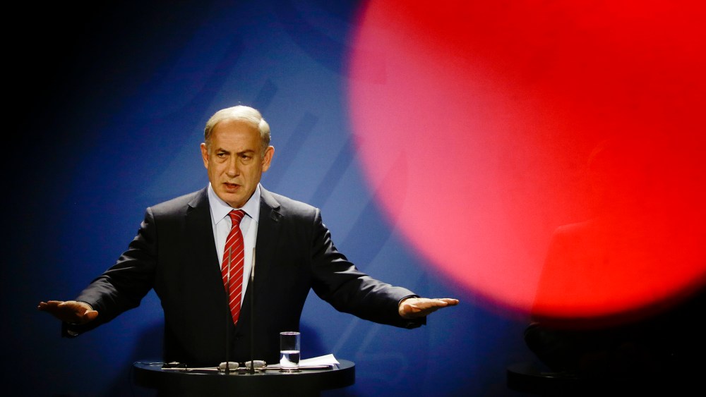 Seen through the silhouette of a cameraman, Israeli Prime Minister Benjamin Netanyahu speaks at a news conference with German Chancellor Angela Merkel during a meeting at the chancellery in Berlin, Oct. 21, 2015. (Photo by Markus Schreiber/AP)
