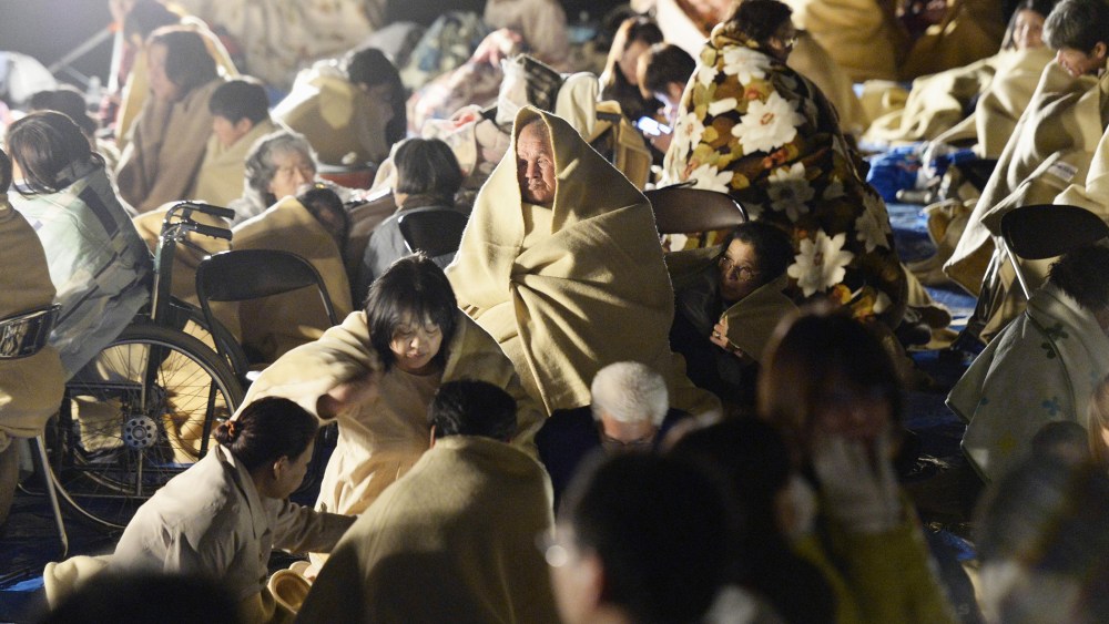 Residents wrap themselves in blankets as they take shelter outside the town hall of Mashiki, near Kumamoto city, southern Japan, after the earthquake early April 15, 2016. (Photo by Ryosuke Uematsu/Kyodo News/AP)