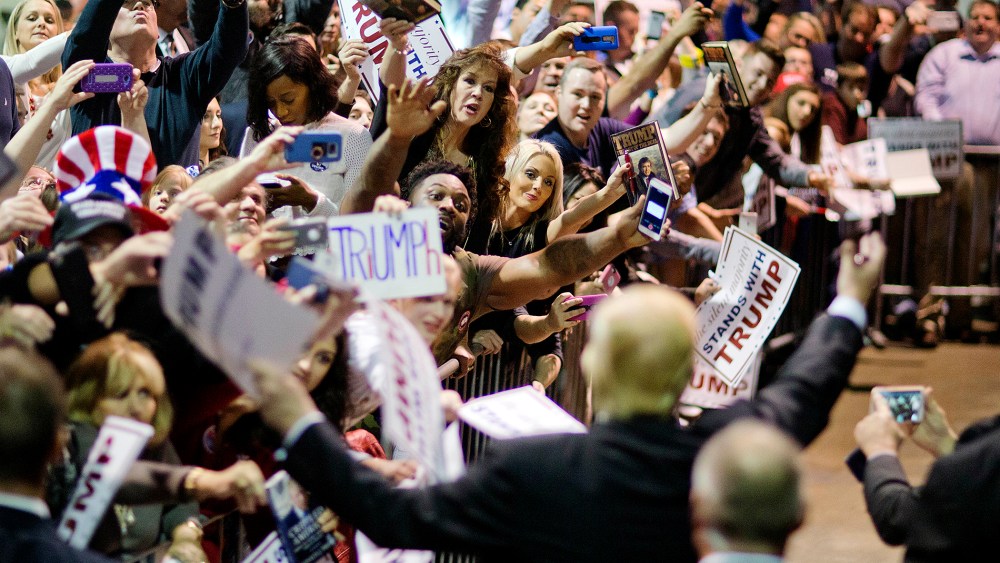 Audience members cheer as Republican presidential candidate Donald Trump signs autographs at a campaign event, Feb. 21, 2016, in Atlanta, Ga. (Photo by David Goldman/AP)