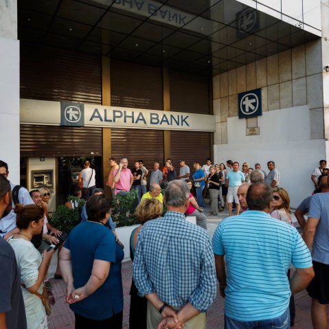 People stand in a queue to use ATM cash machine of a bank in central Athens on June 28, 2015. (Photo by Daniel Ochoa de Olza/AP)