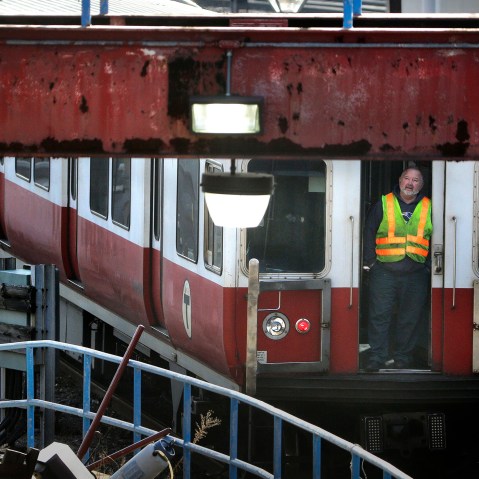 A worker stands at an entrance to a passenger train as it rests on tracks, Dec. 10, 2015, in Boston. (Photo by Steven Senne/AP)