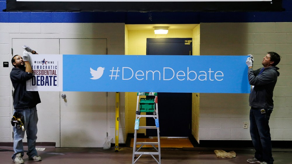 Workers Daniel Rodriguez, left, and Chad Parson hang a sign in the media filing center before Saturday night's Democratic Presidential Debate, Nov. 13, 2015, in Des Moines, Iowa. (Photo by Charlie Neibergall/AP)