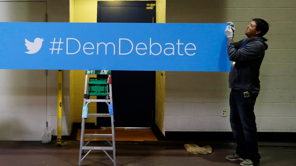 A sign for the Democratic debate hashtag is hung in the media filing center before the Nov. 13, 2015 Democratic Presidential Debate in Des Moines, Iowa. (Photo by Charlie Neibergall/AP)