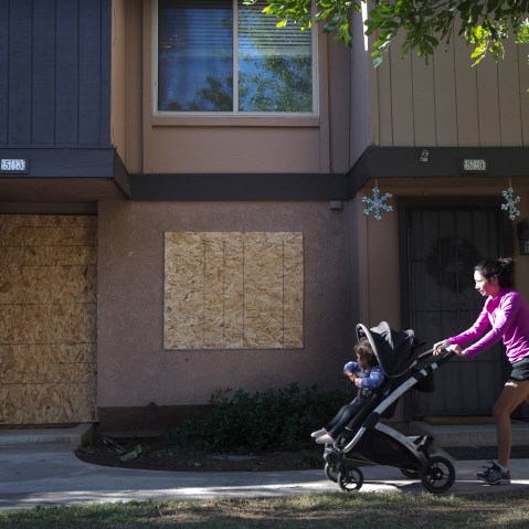 A woman pushes a baby stroller past the boarded-up townhouse rented by San Bernardino shooting rampage suspects Syed Farook and his wife, Tashfeen Malik, Saturday, Dec. 5, 2015, in Redlands, Calif. (Photo by Jae C. Hong/AP)