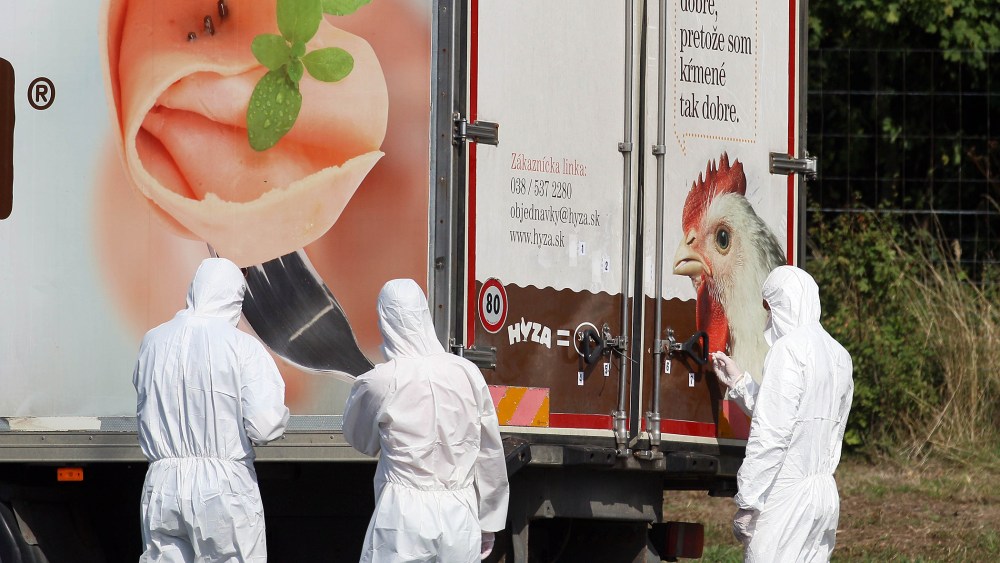 Investigators stand near a truck that stands on the shoulder of the highway A4 near Parndorf south of Vienna, Austria on Aug. 27, 2015. (Photo by Ronald Zak/AP)
