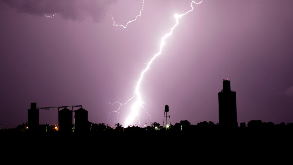 Grain elevators are silhouetted against lightning as a thunderstorm passes in the distance, June 4, 2015, in Collyer, Kan. (Photo by Charlie Riedel/AP)