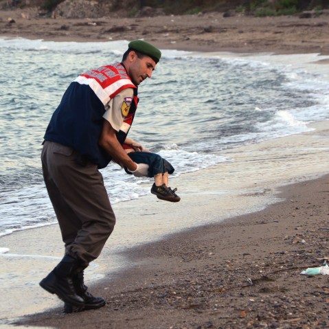 A paramilitary police officer carries the lifeless body of a migrant child near the Turkish resort of Bodrum early Wednesday, Sept. 2, 2015. (Photo by DHA/AP)