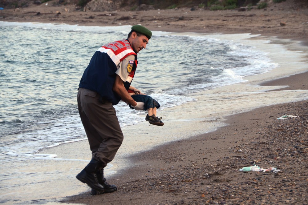 A paramilitary police officer carries the lifeless body of a migrant child near the Turkish resort of Bodrum early Wednesday, Sept. 2, 2015. (Photo by DHA/AP)