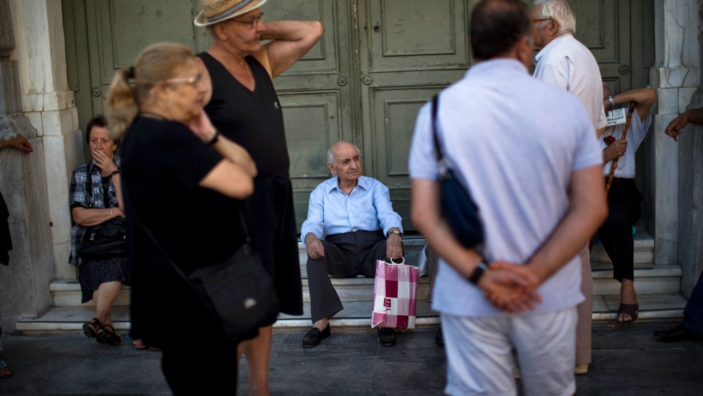 Pensioners sit at the main gate of the national bank of Greece as they wait to withdraw a maximum of 120 euros ($134) for the week in central Athens, July 13, 2015. (Photo by Emilio Morenatti/AP)