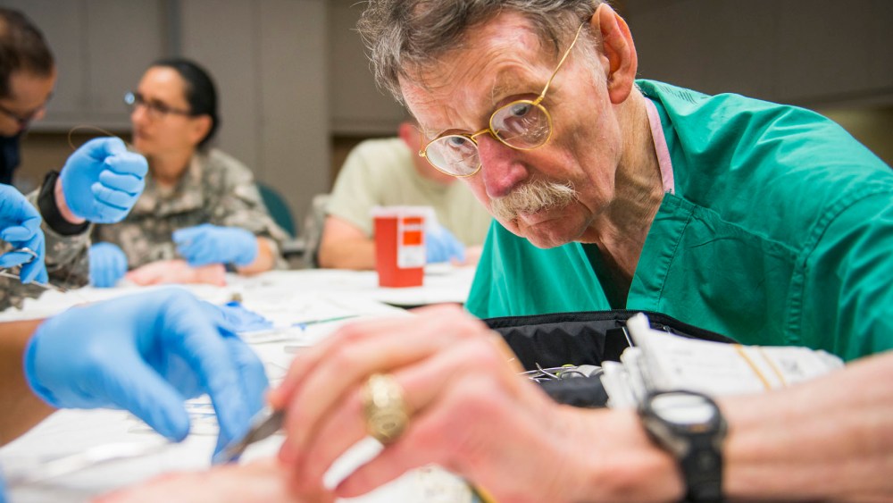 Dr. James "Red" Duke instructs a group of U.S. Army flight medics in suturing techniques using pigs feet at Memorial Hermann Hospital in Houston, Texas on Aug. 15, 2013. (Photo by Smiley N. Pool/Houston Chronicle/File/AP)