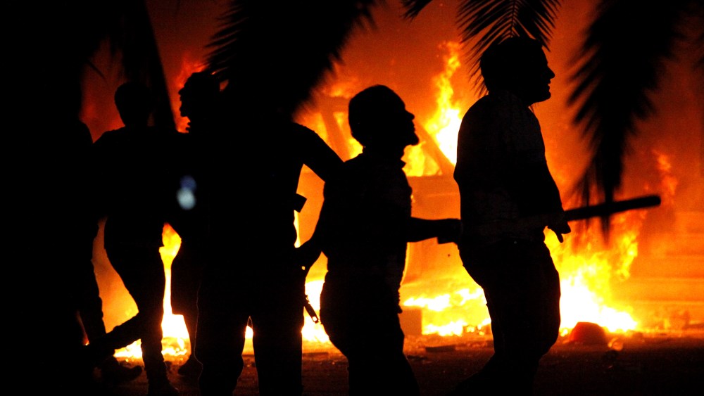In this Friday, Sept. 21, 2012 file photo, Libyan civilians watch fires at an Ansar al-Shariah Brigades compound, after hundreds of Libyans, Libyan Military, and Police raided the Brigades base, in Benghazi, Libya. (Photo by Mohammad Hannon/AP)