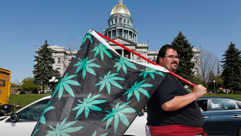 Kris Custer of Denver waves a flag in support of marijuana in front of the State Capitol, April 20, 2015, in Denver, Co. (Photo by David Zalubowski/AP)