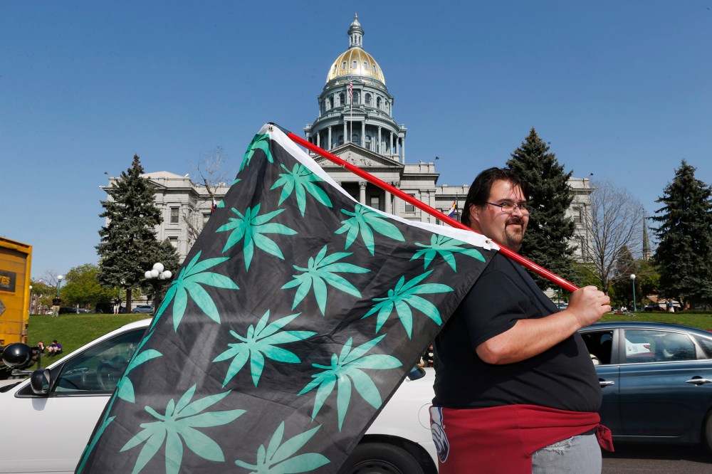 Kris Custer of Denver waves a flag in support of marijuana in front of the State Capitol, April 20, 2015, in Denver, Co. (Photo by David Zalubowski/AP)