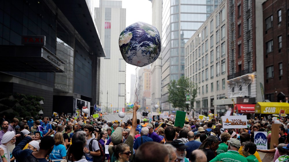 A man holds an earth balloon into the air as people fill the street before a global warming march in New York Sunday, Sept. 21, 2014. (Photo by Mel Evans/AP)