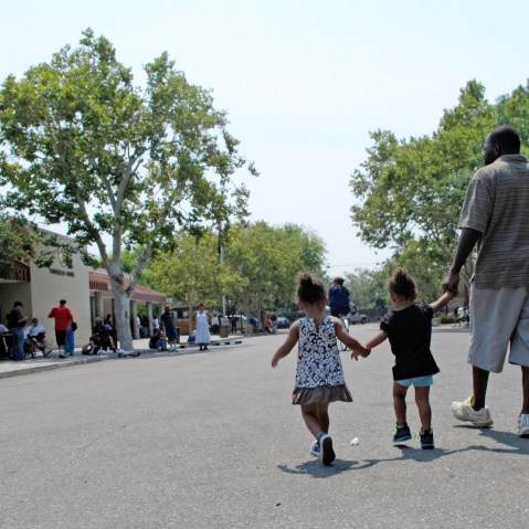 A man walks with two children outside the Poverello House homeless shelter Thursday, July 31, 2014, in Fresno, Calif. (Photo by Scott Smith/AP)