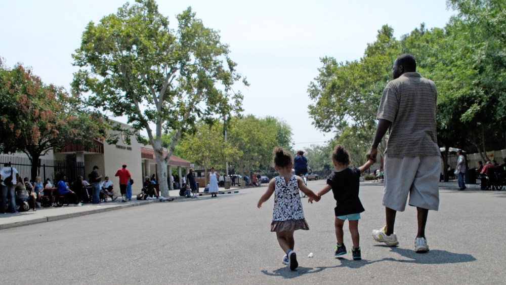 A man walks with two children outside the Poverello House homeless shelter Thursday, July 31, 2014, in Fresno, Calif. (Photo by Scott Smith/AP)