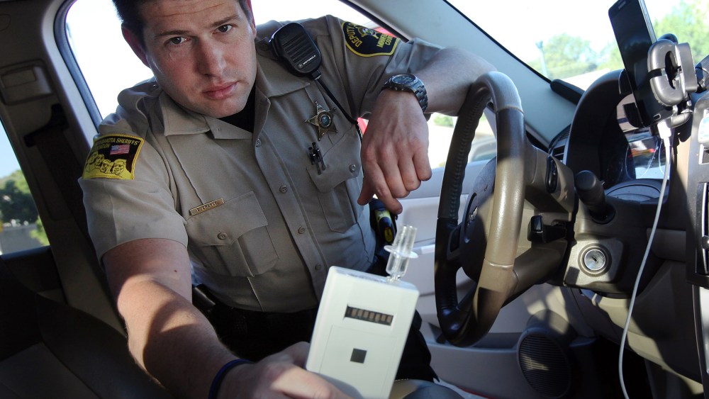 In this Sept. 21, 2015 photo, Minnehaha County Deputy Sheriff Elliott Crayne installs a car breathlyzer outside the county jail in Sioux Falls, S.D. (Photo by Jay Pickthorn/AP)
