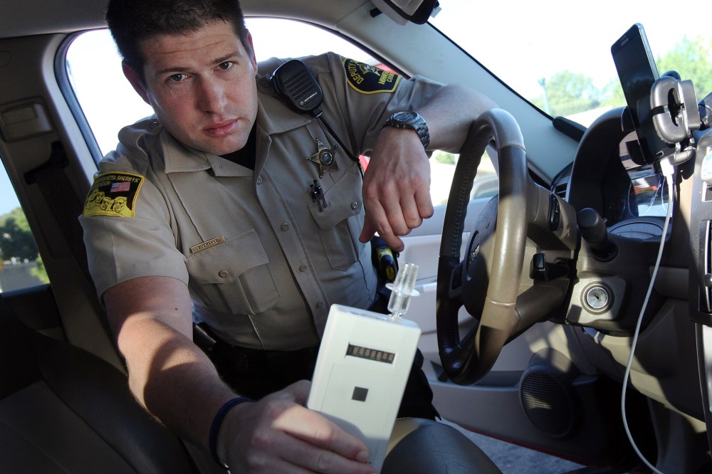 In this Sept. 21, 2015 photo, Minnehaha County Deputy Sheriff Elliott Crayne installs a car breathlyzer outside the county jail in Sioux Falls, S.D. (Photo by Jay Pickthorn/AP)