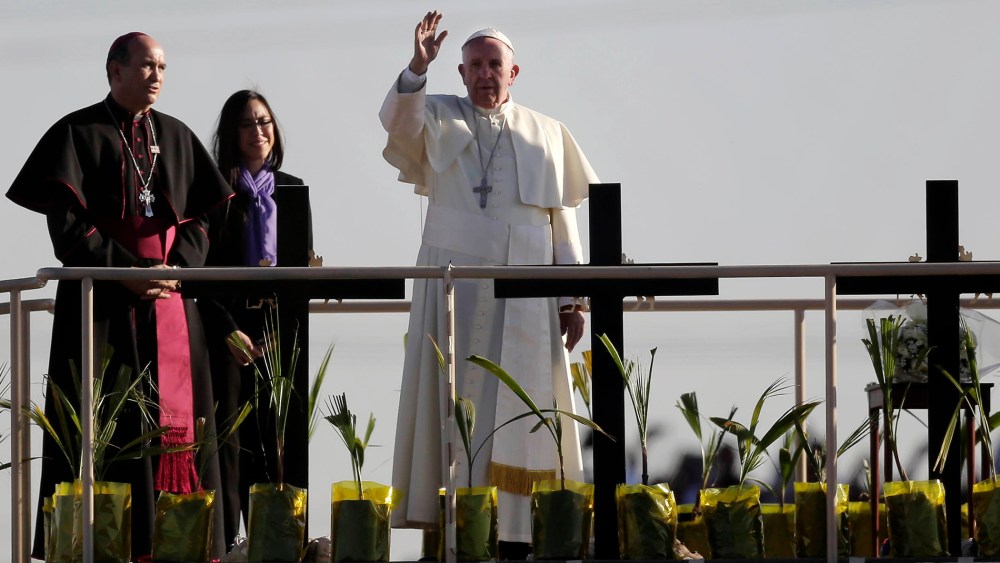 Pope Francis stands on a platform near the U.S.-Mexico border fence along the Rio Grande, in Ciudad Juarez, Mexico, Feb. 17, 2016, as he blesses a group of migrants. (Photo by Eric Gay/AP)