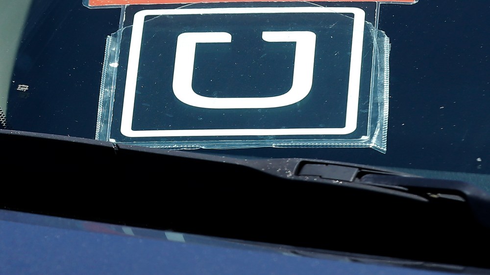 An Uber sign is displayed on a driver's car, July 15, 2015. (Photo by Jeff Chiu/AP)