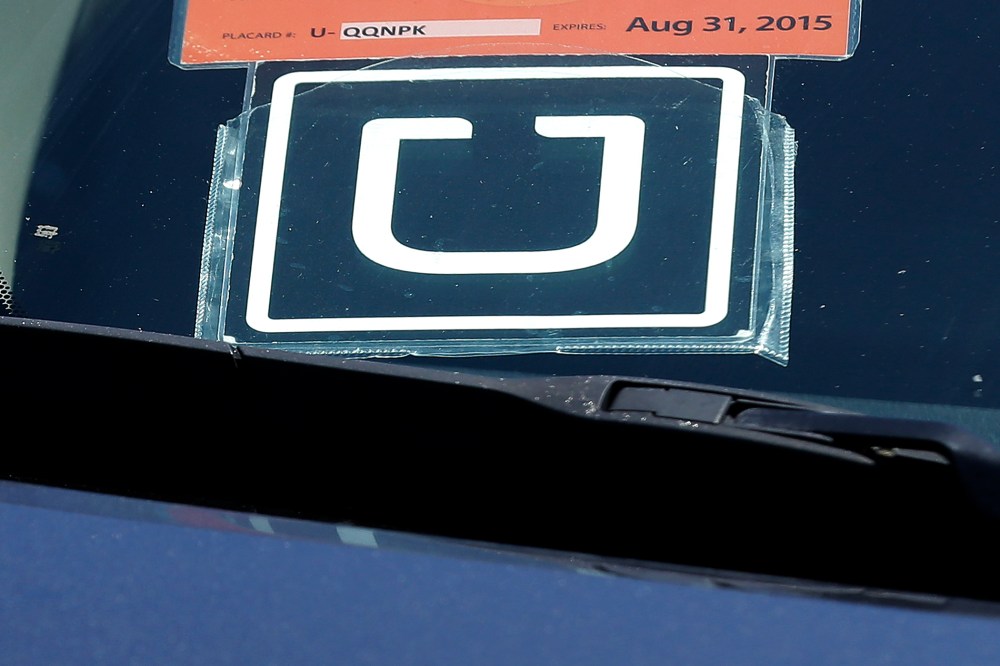 An Uber sign is displayed on a driver's car, July 15, 2015. (Photo by Jeff Chiu/AP)