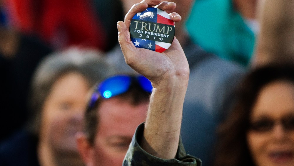A man holds up a campaign button for Republican presidential candidate Donald Trump during a rally, Feb. 28, 2016, in Madison, Ala. (Photo by John Bazemore/AP)