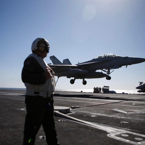 A U.S. Navy crew member looks at an F/A-18 Super Hornet fighter landing onto the deck of the USS Ronald Reagan, during a joint naval drill between South Korea and the U.S. in the West Sea, South Korea, Oct. 28, 2015. (Photo by Kim Hong-ji/Pool/AP)