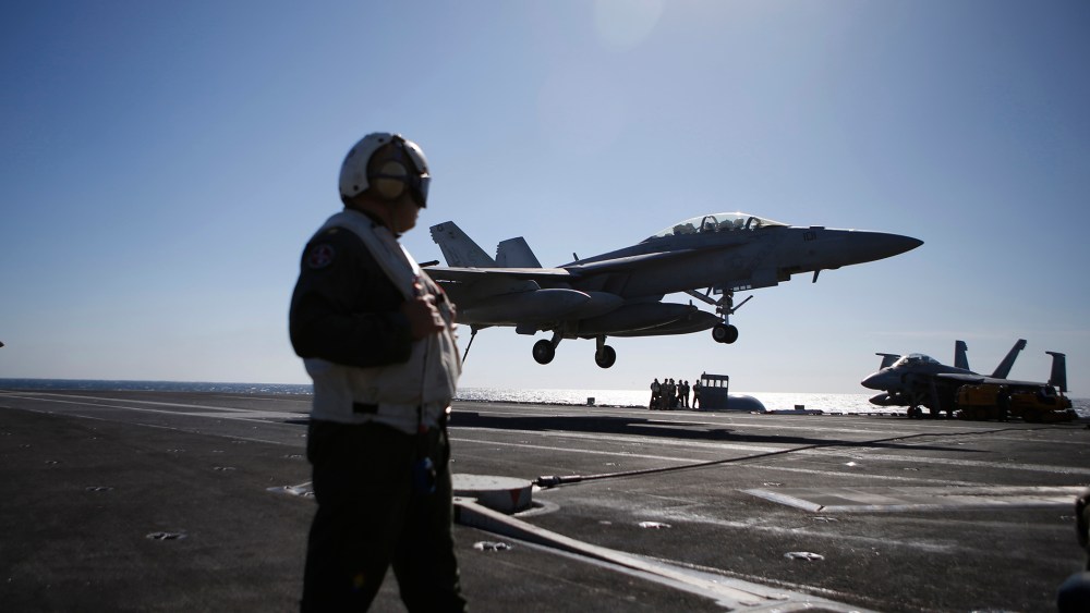 A U.S. Navy crew member looks at an F/A-18 Super Hornet fighter landing onto the deck of the USS Ronald Reagan, during a joint naval drill between South Korea and the U.S. in the West Sea, South Korea, Oct. 28, 2015. (Photo by Kim Hong-ji/Pool/AP)