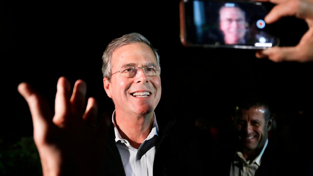 In this Nov. 3, 2015, photo Republican presidential candidate, former Florida Gov. Jeb Bush is recorded as he speaks into a mobile phone while departing a campaign event in Rye, N.H. (Photo by Steven Senne/AP)
