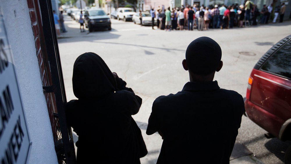 A couple watch from across the street during a news conference outside the Charleston NAACP office regarding the shooting death of Walter Scott by a North Charleston police officer, Thursday, April 9, 2015. (Photo by David Goldman/AP)