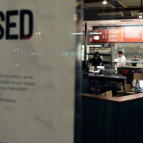 People stand inside a closed Chipotle restaurant on Dec. 7, 2015, in Boston, Mass. (Photo by Steven Senne/AP)