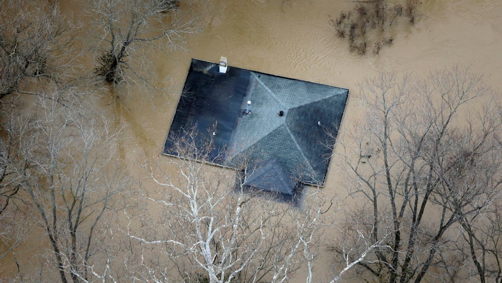In this aerial photo, floodwater reaches the rooftop of a house, Dec. 31, 2015, in Valley Park, Mo. (Photo by Jeff Roberson/AP)