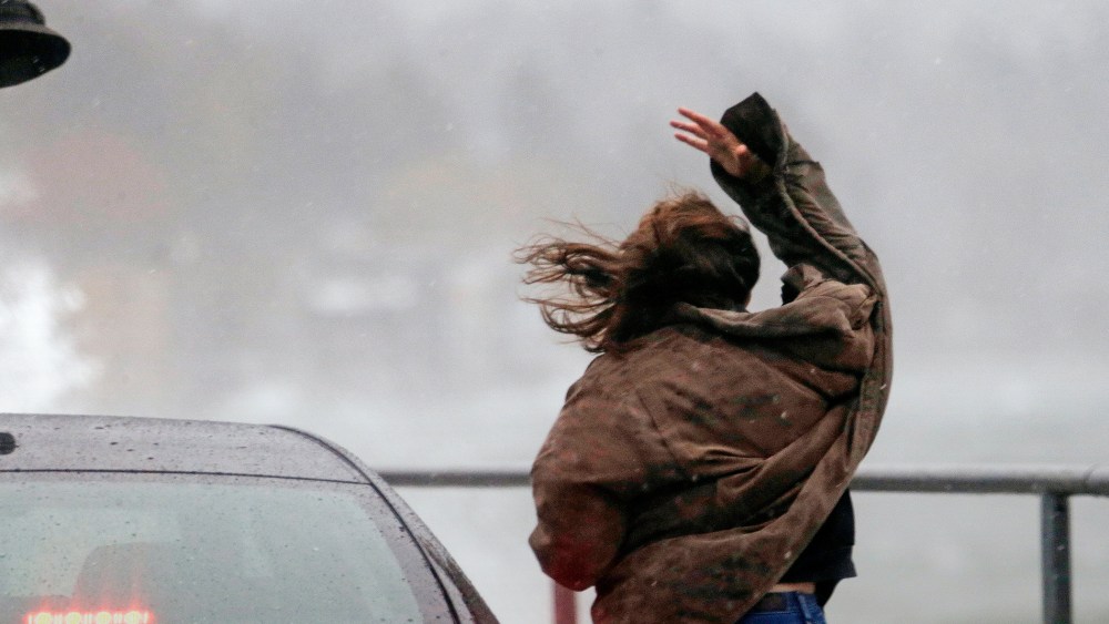 A woman loses her hat to the wind as she steps out of her car to look at high waves, Nov. 17, 2015, in the West Seattle neighborhood of Seattle. (Photo by Elaine Thompson/AP)
