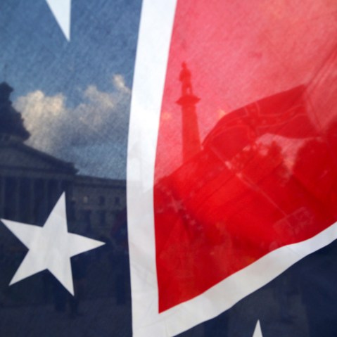 The South Carolina State House is seen through a Confederate flag held along Gervais Street on July 6, 2015, in Columbia, S.C. (Photo by Gerry Melendez/The State/AP)
