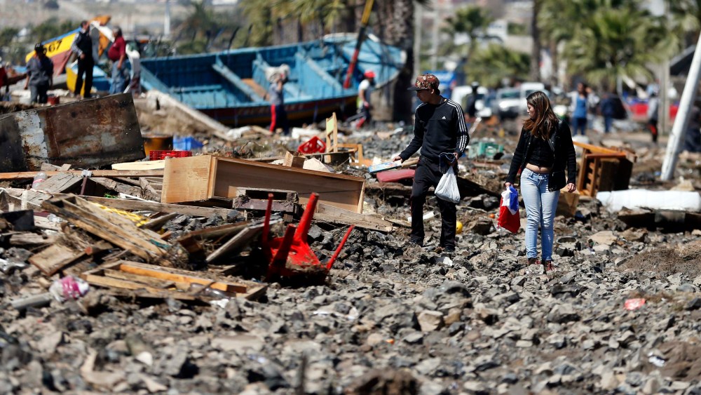 People walk through debris left behind by an earthquake-triggered tsunami in the coastal town of Coquimbo, Chile on Sept. 17, 2015. (Photo by Luis Hidalgo/AP)