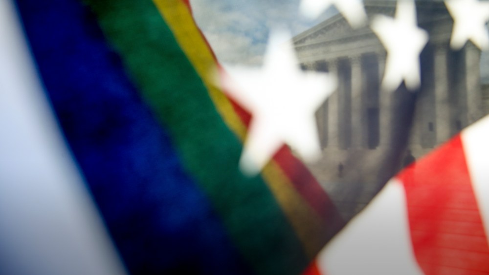 A rainbow colored flag, seen through an American flag, flies in front of the Supreme Court in Washington. (Photo by Andrew Harnik/AP)