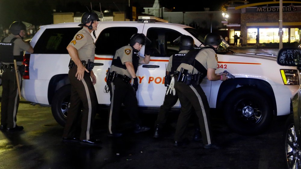 Members of the St. Louis County Police Department take cover at a protest in Ferguson, Mo., Aug. 9, 2015. (Photo by Jeff Roberson/AP)