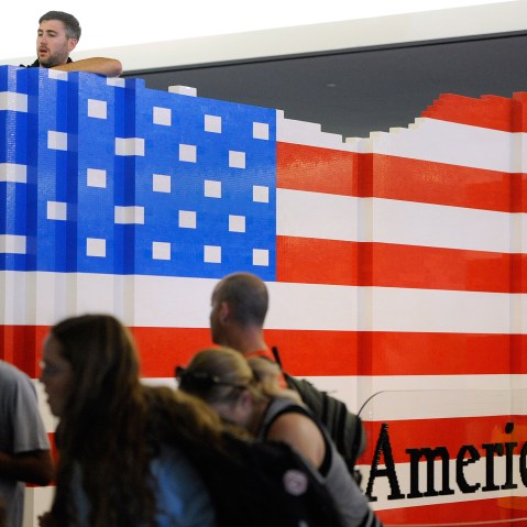 LEGO master builder Chris Steininger places a brick while building the world's largest LEGO American flag to celebrate the opening of the Innovation Wing at the National Museum of American History (Photo by Steve Ruark/AP).