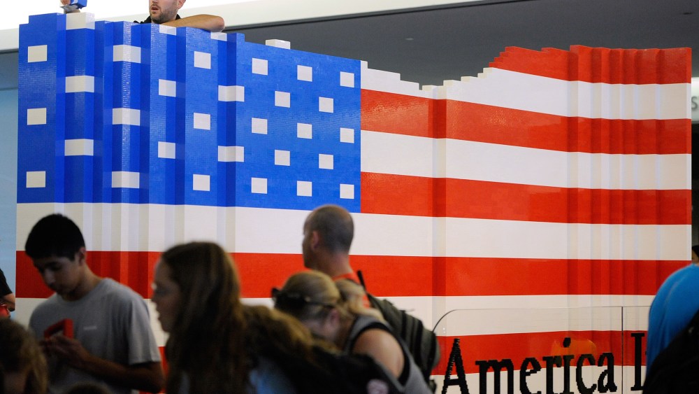 LEGO master builder Chris Steininger places a brick while building the world's largest LEGO American flag to celebrate the opening of the Innovation Wing at the National Museum of American History (Photo by Steve Ruark/AP).