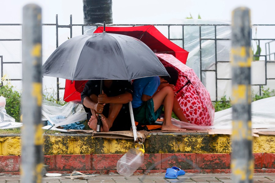 Residents huddle together under their umbrellas as strong winds and slight rain are brought by Typhoon Koppu Oct. 18, 2015 in Manila, Philippines. (Photo by Bullit Marquez/AP)